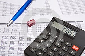 Black calculator, pen, small house