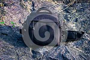 Black camera bag on rocks background