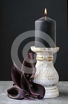 Black candle and black calla flowers (Zantedeschia).