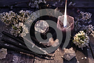 Black candles, crystal and sprig flowers on witch table