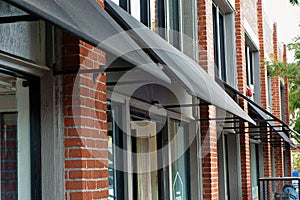 Black canvas awnings projecting out from a brick wall.