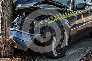 Black car drives head-on against tree