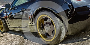 Black car with gold wheel rim and black spokes