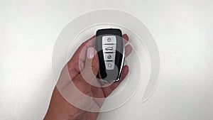 A black car key with metal inserts and automatic buttons is taken by the hand of a person of European appearance, runs