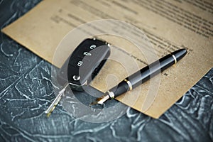 Black car key and money on a signed contract of car sale.