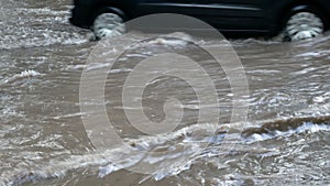 Black car moving through road after heavy downpour with deep water