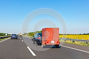 Black car with red carry-on cargo trailer on the highway