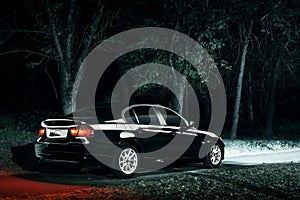 Black car stay in darkness forest at night