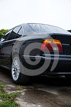 black car in the yard in water drops after rain with