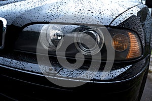 black car in the yard in water drops after rain with