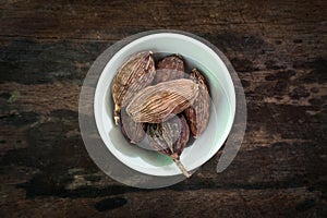 Black Cardamom Tsaoko Fruit on blow over wooden background