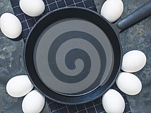 Black cast-iron frying pan on black cloth, white chicken eggs. B