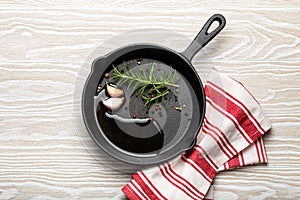 Black cast iron frying pan with rosemary, garlic, pepper, oil