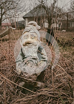 A black cat behind an old garden figure in a creepy photo