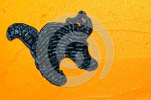 Black cat with orange eyes on orange frosting