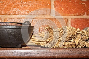 Black cauldron with an armful of wheat on a wooden shelf