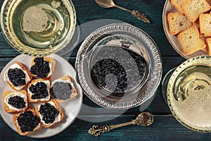 Black caviar with champagne in vintage coupe glasses, with toasts, a flat lay, top shot