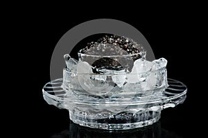 Black caviar in ice on a black photo