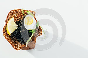 Black caviar on a sandwich with eggs, lemon, greenery