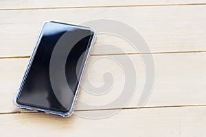 Black cell phone on wooden board, top view