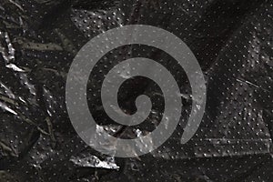 black cellophane bag background texture. plastic surface is wrinkly and tattered making abstract pattern