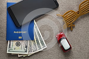 Black cellphone, money American dollars banknotes bills, passport, toy car and funny sunglasses on copy space background, top view