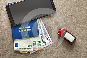 Black cellphone, money euro banknotes bills, passport and toy car on copy space background. Travel light, comfortable journey