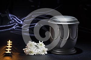 Black cemetery urn with burning candles white chrysanthemum on deep blue background