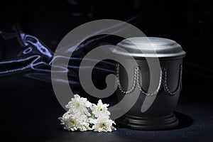 Black cemetery urn with white chrysanthemum, on deep blue background