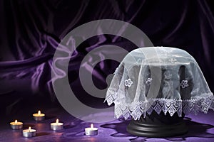 Black cemetery urn with white shroud candles on deep purple background