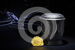 Black cemetery urn with yellow rose on deep blue background