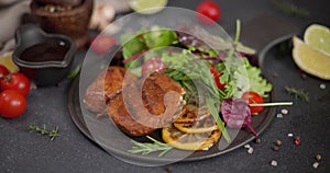 Black ceramic plate with Fried grilled pieces of Organic Tuna Steak and salad