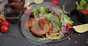 Black ceramic plate with Fried grilled pieces of Organic Tuna Steak and salad