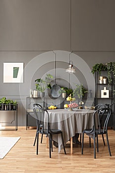 Black chairs at round table under lamp in grey dining room inter