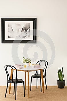 Black chairs standing by wooden dining table with juice, pastel