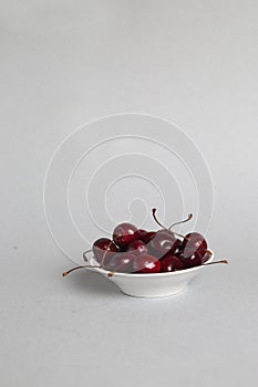 Black cherries in a bowl isolated on gray background