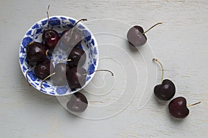 Black cherries on a white and blue vintage bowl over woodwn table
