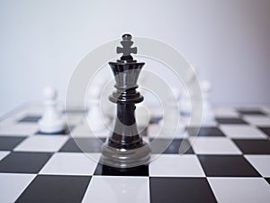 A black chess king stand in front of white chess enemy on board, challenges planning business strategy to success concept