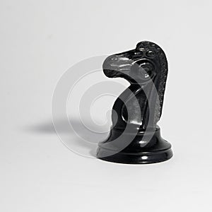 Black chess knight on a white background, tight shadow