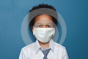 Black child boy student in medical protective face mask on blue background