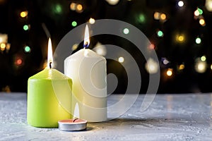 black Christmas background with colorful lights and burning candles in the foreground