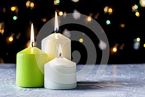 black Christmas background with colorful lights and burning candles in the foreground