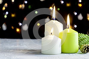 Black Christmas background with colorful lights and burning candles in the foreground