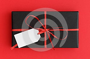 Black christmas gift with a blank tag mockup on a red background