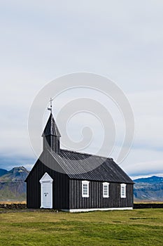 Black church in the meadow and field in Iceland. Icelandic scenic travel destination of religion.