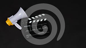 Black Clapperboard or movie clapper board and Megaphone in yellow color isolated on black background