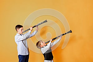 Black clarinet on an orange background in the hands of young performers of the folk mazy. Two brothers with clarinets, performing