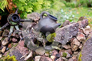 Black clay jug and old wooden barrel on stone pile