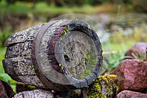 Black clay jug and old wooden barrel on stone pile