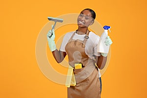 black cleaner woman holding detergent spray bottle and squeegee, studio